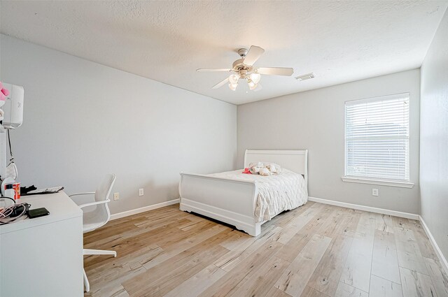 bedroom featuring ceiling fan, light hardwood / wood-style flooring, and a textured ceiling