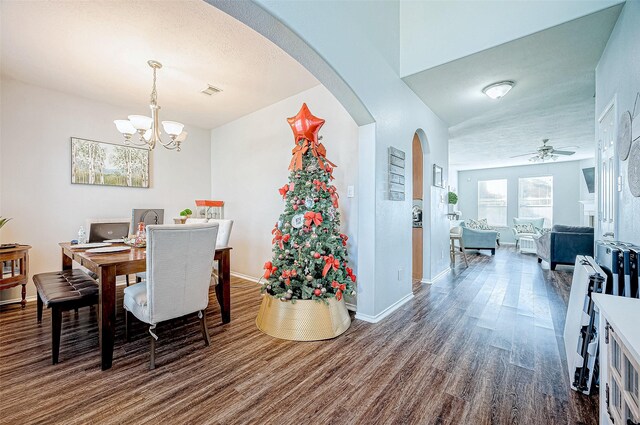 dining room featuring dark hardwood / wood-style flooring, ceiling fan with notable chandelier, and a textured ceiling