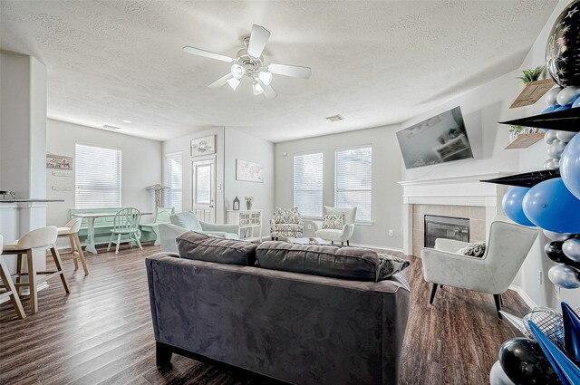 living room with a textured ceiling, ceiling fan, wood-type flooring, and a fireplace