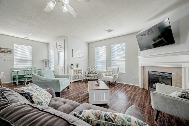 living room with a textured ceiling, ceiling fan, dark hardwood / wood-style floors, and a fireplace