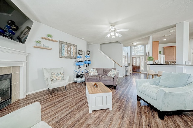 living room with ceiling fan, wood-type flooring, and a fireplace