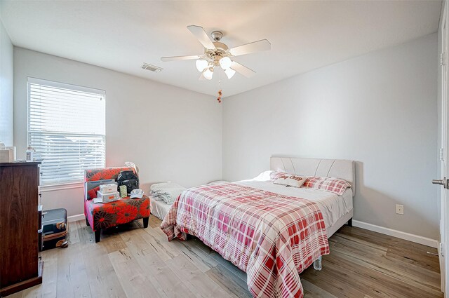 bedroom with multiple windows, hardwood / wood-style floors, and ceiling fan