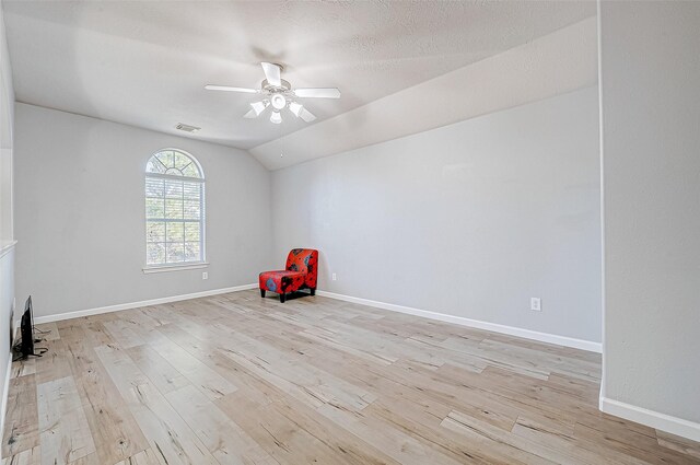 interior space with ceiling fan, light wood-type flooring, lofted ceiling, and a textured ceiling