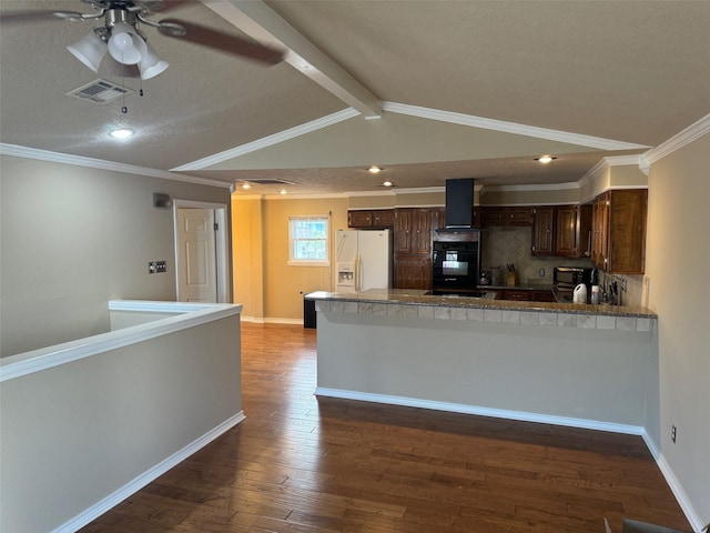 kitchen featuring wall chimney range hood, tasteful backsplash, dark hardwood / wood-style floors, white refrigerator with ice dispenser, and kitchen peninsula