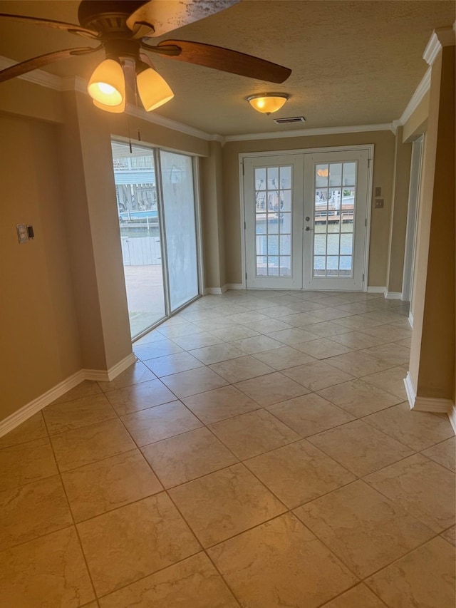 tiled empty room with french doors, a textured ceiling, ceiling fan, and ornamental molding