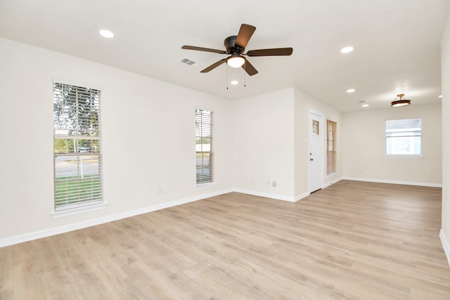 empty room featuring ceiling fan, plenty of natural light, and light wood-type flooring