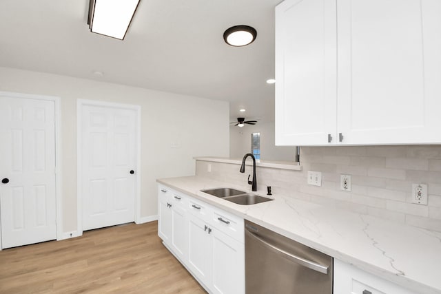 kitchen with stainless steel dishwasher, light stone countertops, white cabinetry, and sink