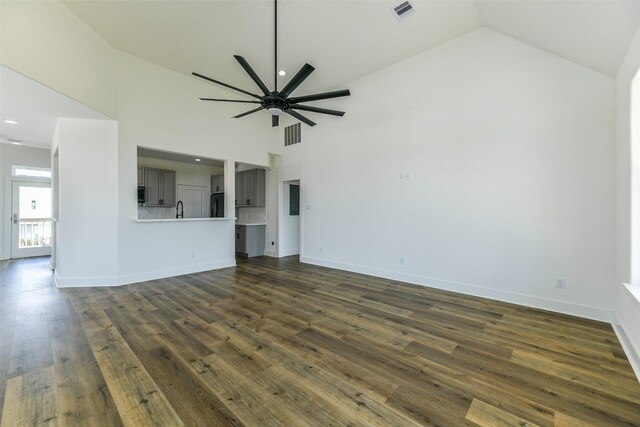 unfurnished living room with dark hardwood / wood-style flooring, high vaulted ceiling, ceiling fan, and sink