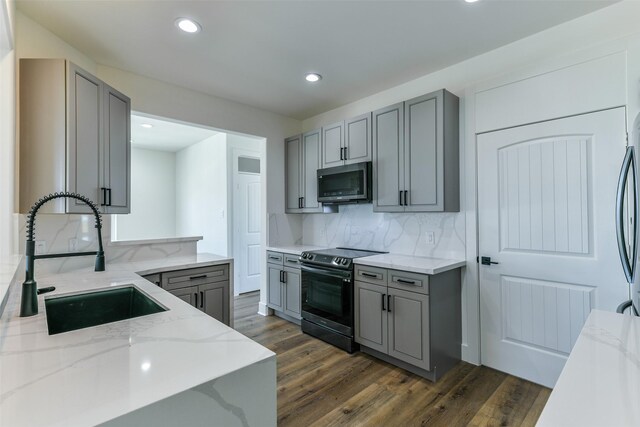 kitchen with gray cabinetry, backsplash, sink, electric range, and light stone counters