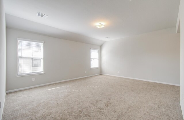 empty room with light colored carpet and vaulted ceiling