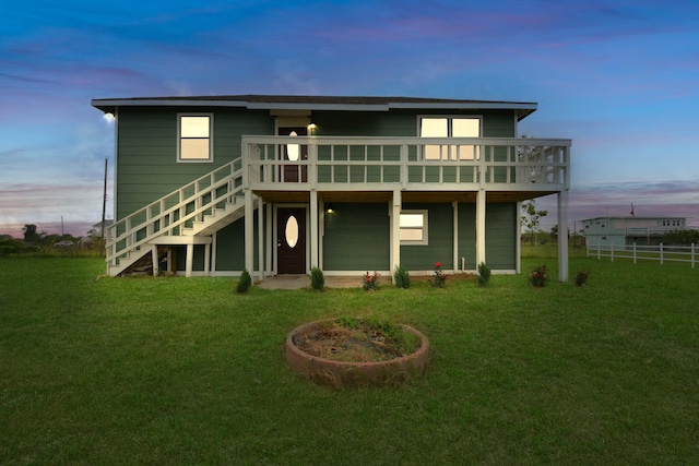 back house at dusk featuring a yard and a deck