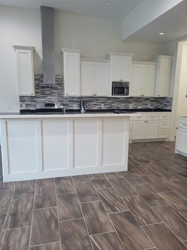 kitchen featuring white cabinetry, built in microwave, wall chimney range hood, and stainless steel range oven