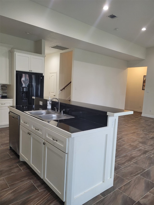 kitchen featuring white cabinets, black fridge, sink, dishwasher, and an island with sink