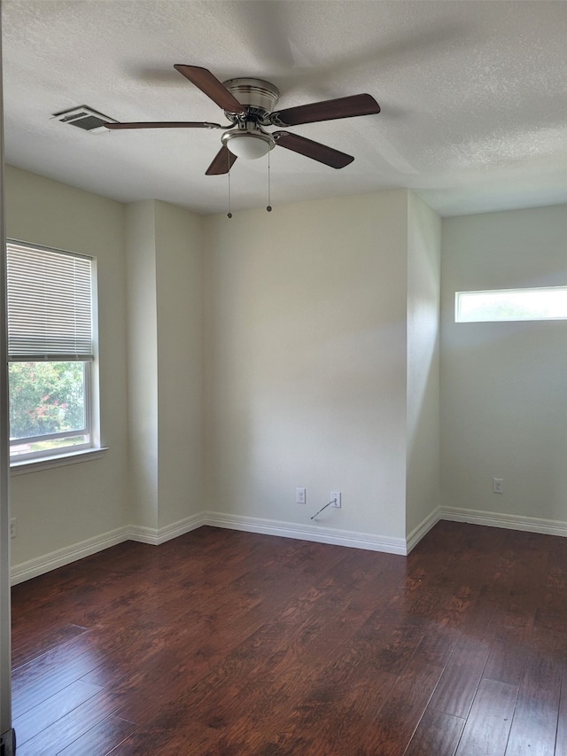 empty room featuring ceiling fan, dark wood-type flooring, and a textured ceiling