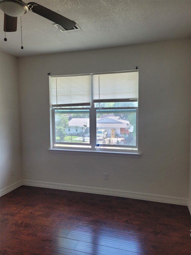 empty room with ceiling fan, dark hardwood / wood-style flooring, and a textured ceiling