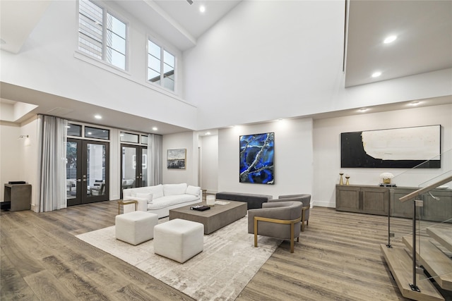 living room featuring french doors, a towering ceiling, and hardwood / wood-style floors