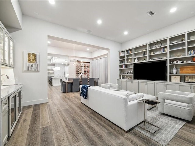 living room featuring built in shelves, a chandelier, and hardwood / wood-style flooring