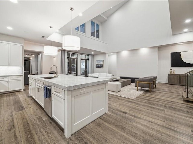 kitchen with white cabinetry, sink, a kitchen island with sink, and decorative light fixtures