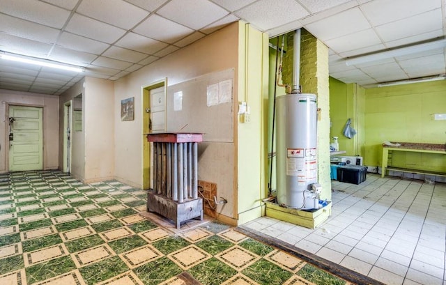 basement featuring water heater and a drop ceiling