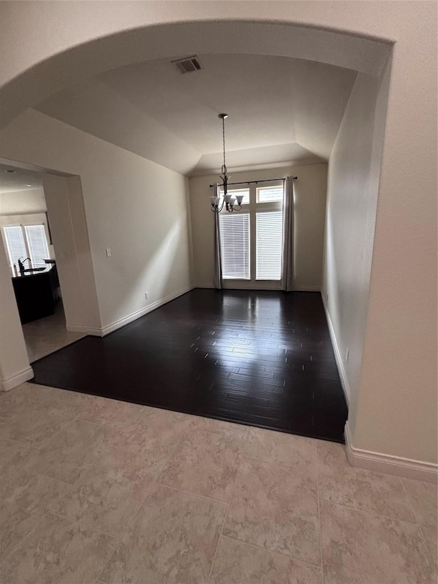 spare room featuring hardwood / wood-style flooring, lofted ceiling, a wealth of natural light, and a chandelier