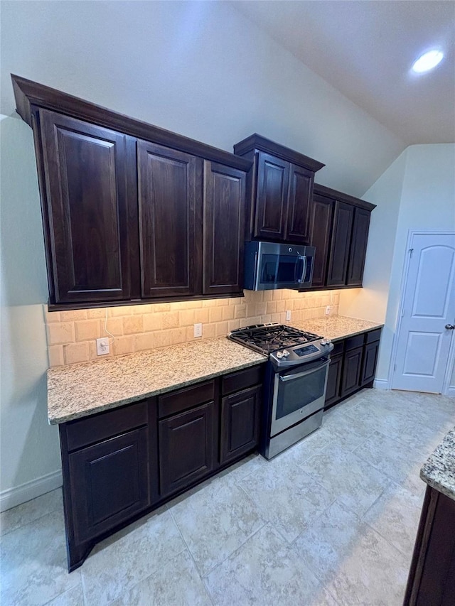 kitchen featuring light stone countertops, appliances with stainless steel finishes, tasteful backsplash, and vaulted ceiling