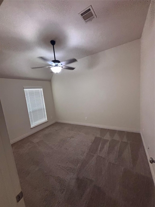 carpeted empty room with a textured ceiling, vaulted ceiling, and ceiling fan