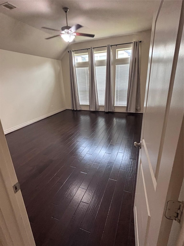 empty room featuring vaulted ceiling, ceiling fan, and dark wood-type flooring