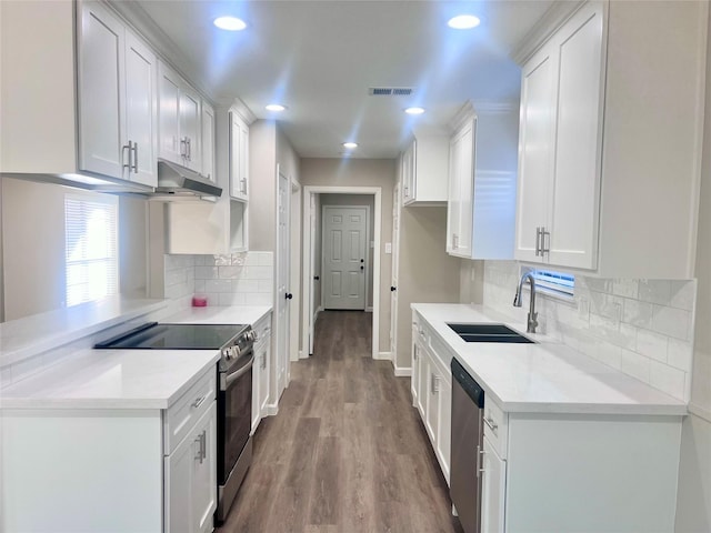 kitchen featuring decorative backsplash, appliances with stainless steel finishes, sink, white cabinets, and hardwood / wood-style floors