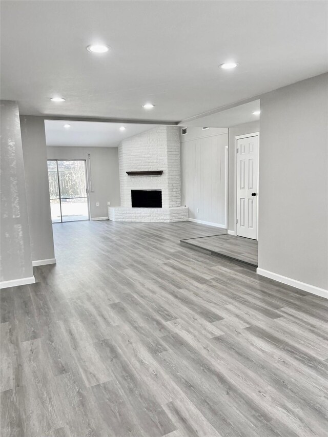 unfurnished living room featuring light hardwood / wood-style flooring and a brick fireplace