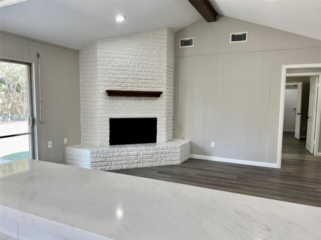 unfurnished living room with a fireplace, lofted ceiling with beams, and dark wood-type flooring