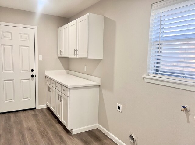 laundry room featuring cabinets, electric dryer hookup, and dark wood-type flooring