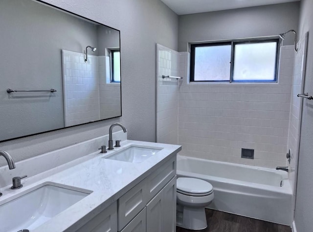 full bathroom with vanity, wood-type flooring, tiled shower / bath combo, and toilet