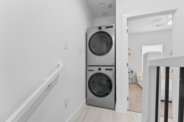 laundry area featuring ceiling fan, light hardwood / wood-style flooring, and stacked washer and clothes dryer