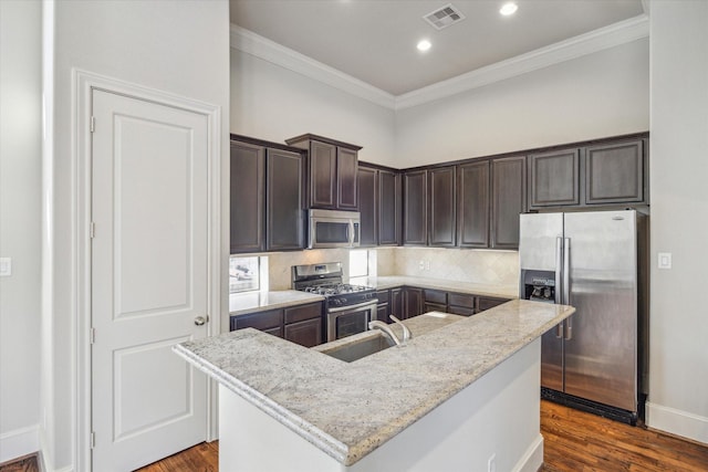 kitchen featuring stainless steel appliances, decorative backsplash, sink, light stone counters, and a center island with sink