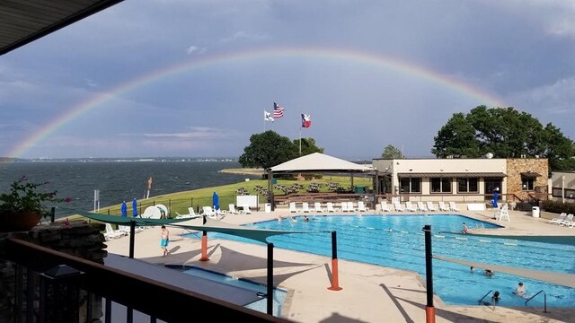 view of pool featuring a water view and a patio