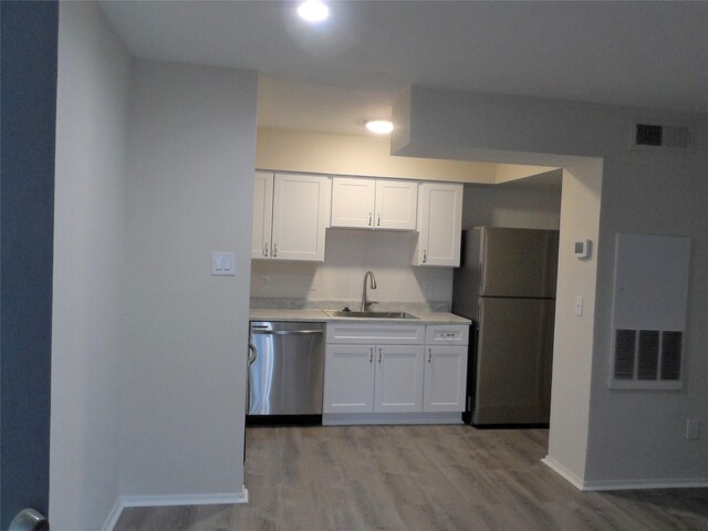 kitchen featuring white cabinetry, sink, light wood-type flooring, and appliances with stainless steel finishes