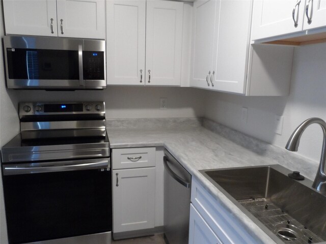 kitchen featuring appliances with stainless steel finishes, white cabinetry, and sink