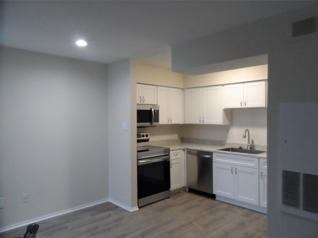 kitchen with sink, white cabinets, stainless steel appliances, and light wood-type flooring