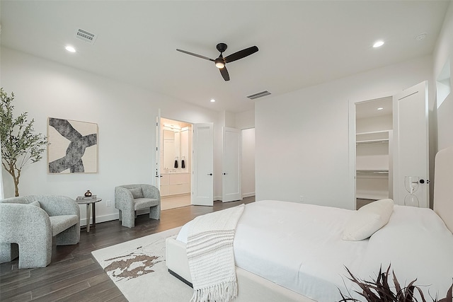 bedroom featuring ceiling fan, ensuite bathroom, dark hardwood / wood-style floors, a walk in closet, and a closet