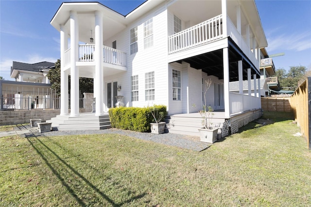 rear view of property featuring a balcony and a yard