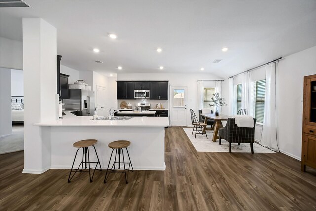 kitchen with sink, dark hardwood / wood-style floors, appliances with stainless steel finishes, a kitchen bar, and kitchen peninsula