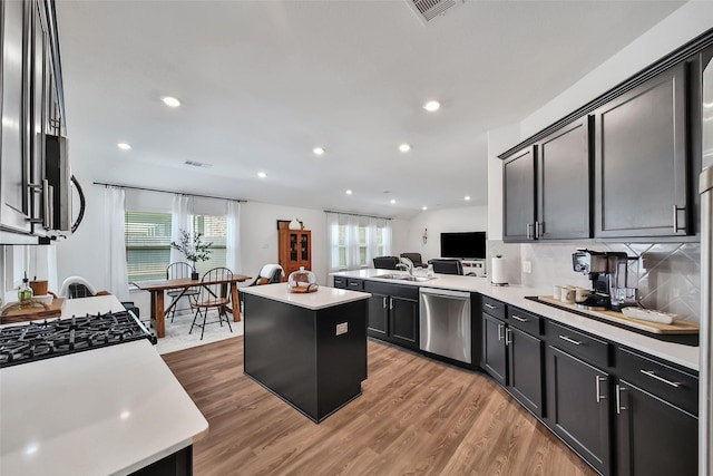 kitchen with kitchen peninsula, sink, dishwasher, a center island, and light hardwood / wood-style floors