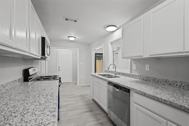 kitchen featuring sink, stainless steel appliances, light stone counters, white cabinets, and light wood-type flooring