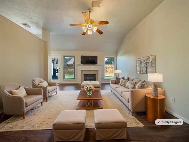 living room featuring a textured ceiling, vaulted ceiling, ceiling fan, a tile fireplace, and hardwood / wood-style floors