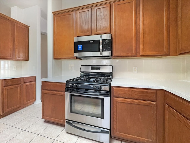 kitchen with appliances with stainless steel finishes, backsplash, and light tile patterned floors