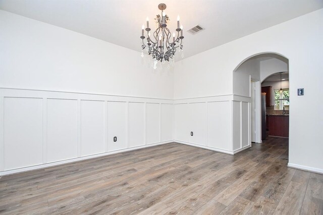 unfurnished room featuring hardwood / wood-style flooring and a notable chandelier