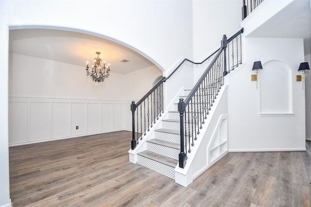 stairs featuring hardwood / wood-style flooring and a notable chandelier