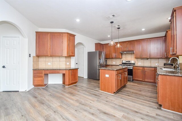 kitchen featuring appliances with stainless steel finishes, a kitchen island, pendant lighting, and dark stone countertops