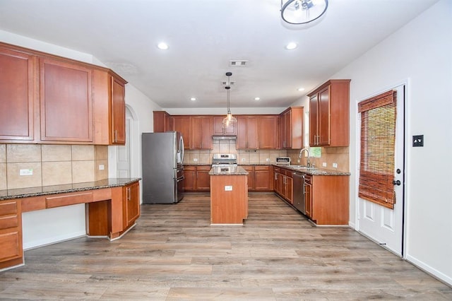 kitchen featuring a center island, pendant lighting, light hardwood / wood-style floors, dark stone counters, and appliances with stainless steel finishes