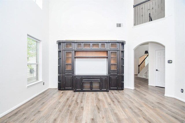 unfurnished living room featuring light hardwood / wood-style floors and a high ceiling